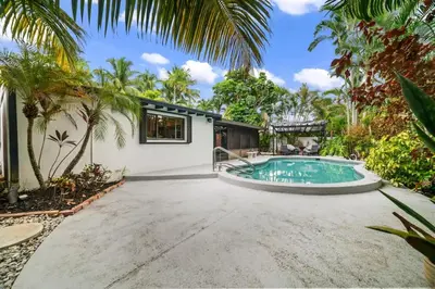 an exterior view of a house with a swimming pool and palm trees at Oasis with Pool & Cold Plunge-Near Beach & Nightlife in Fort Lauderdale