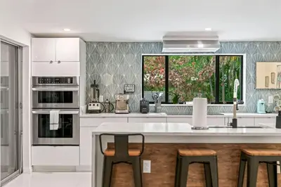 a kitchen with white cabinets and a large window at Oasis with Pool & Cold Plunge-Near Beach & Nightlife in Fort Lauderdale