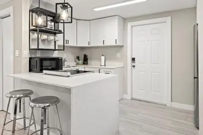 a kitchen with white cabinets and a counter with stools at Perfect stay for 2-Walk to Wilton Drive-Shops &bars in Fort Lauderdale