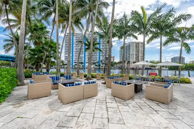 a patio with tables and chairs and palm trees at Amazing Intracoastal Views - Walk to the Beach! in Fort Lauderdale