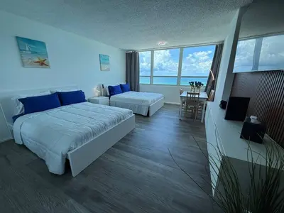 a large hotel room with two beds and a table at 1701 - Studio Ocean Front Free Parking Pool in Miami Beach