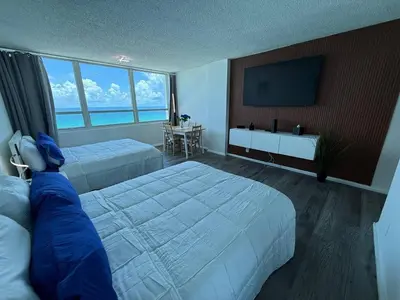 a hotel room with two beds and a flat screen tv at 1701 - Studio Ocean Front Free Parking Pool in Miami Beach