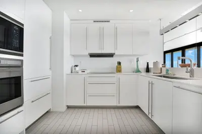 a white kitchen with white cabinets and a wooden floor at Stunning Oceanfront 2BR W Hotel in Miami Beach
