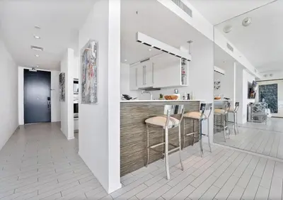a white kitchen with a bar with stools in it at Stunning Oceanfront 2BR W Hotel in Miami Beach