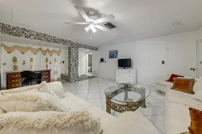 a living room with white furniture and a ceiling fan at Canal-Front Gem with Pool 3 Mi to Hard Rock Stadium in Miramar