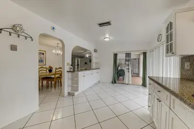 a kitchen with a table and a dining room at Canal-Front Gem with Pool 3 Mi to Hard Rock Stadium in Miramar