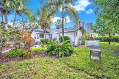 a white house with palm trees in a yard at Bromeliad Bungalow - Downtown Cottage in Fort Lauderdale