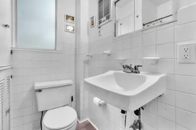 a white bathroom with a sink and a toilet at Bromeliad Bungalow - Downtown Cottage in Fort Lauderdale