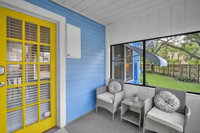 a porch with two chairs and a yellow door at Blue Reverie - Downtown Cottage in Fort Lauderdale