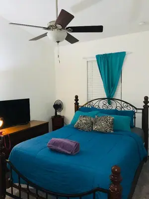 a bedroom with a blue bed with a ceiling fan at Miami Fort Lauderdale Vacation Rooms in Miramar