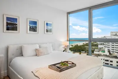a bedroom with a large white bed with a large window at Stunning Ocean View Private Residence at The Setai - 2002 in Miami Beach