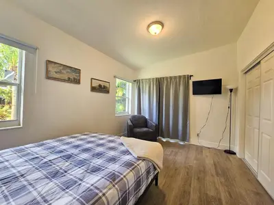 a bedroom with a bed and a chair and a television at Modern 3BR Home Near Holycross Hospital in Fort Lauderdale