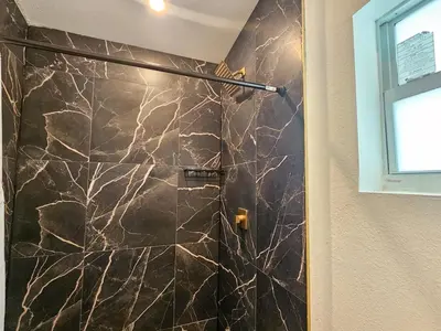 a shower in a bathroom with a marble wall at Modern 3BR Home Near Holycross Hospital in Fort Lauderdale