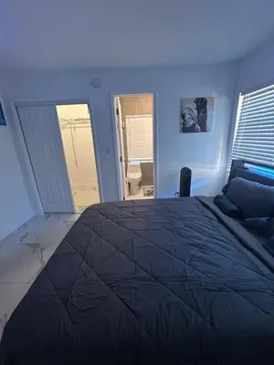 a bedroom with a large bed and a bathroom at Family Willy Michel in Opa-locka