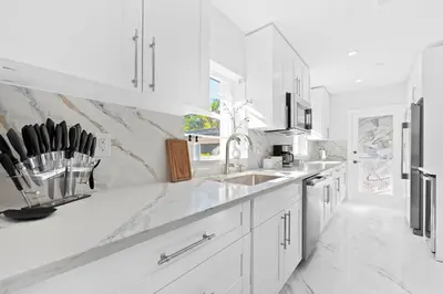 a white kitchen with white cabinets and a sink at Cozy 4BR Pool Villa Near The Beach with Arcades in Fort Lauderdale