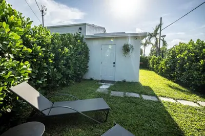 a yard with a white building and a chair at The Side Villa in Miami