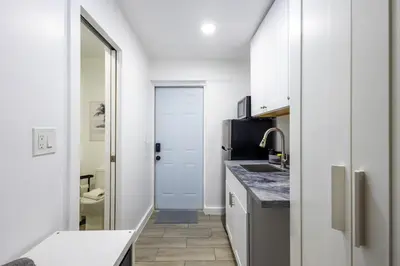 a kitchen with white cabinets and a sink and a door at The Side Villa in Miami