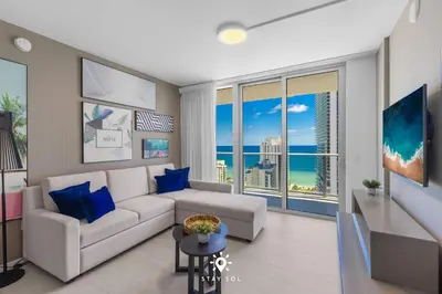 a living room with a white couch and blue pillows at Luxury 2BR Apt With Ocean View Pool & Amenities in Hollywood