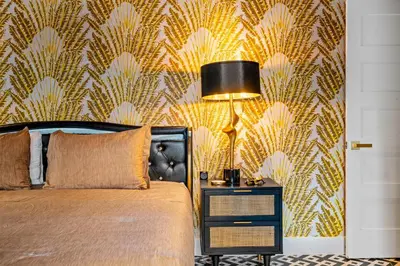 a bedroom with a bed and a wall with gold leaf wallpaper at Beach Pop - Steps to Beach Heated Pool & Hot Tub in Fort Lauderdale