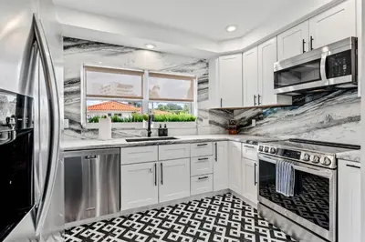 a kitchen with white cabinets and a black and white tile floor at Beach Pop - Steps to Beach Heated Pool & Hot Tub in Fort Lauderdale