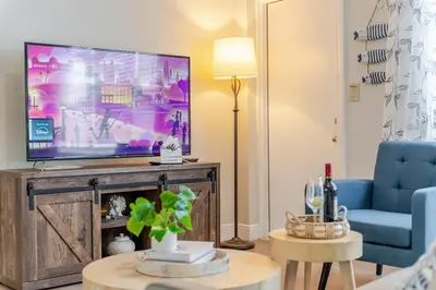 a living room with a large television and a blue couch at Oceanfront Bliss Cozy 1BR by Beach Free Parking in Hollywood
