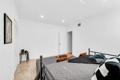 a bedroom with a bed and a white wall at Miami Luxury Home Close to Beach & Aventura Mall in Biscayne Park