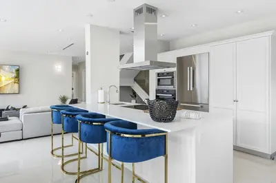 a kitchen with white cabinets and blue bar stools at Villa Costa in Hollywood