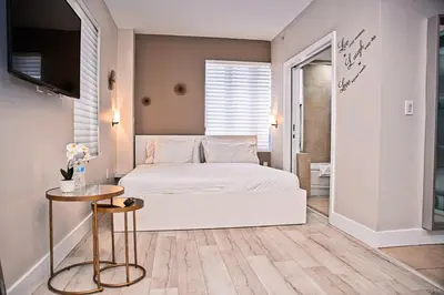 a bedroom with a white bed and a table at Cozy Studio Ocean Drive - Roof Top Pool with Bar in Miami Beach