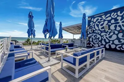 a patio with blue chairs and umbrellas on the beach at Cozy Studio Ocean Drive - Roof Top Pool with Bar in Miami Beach