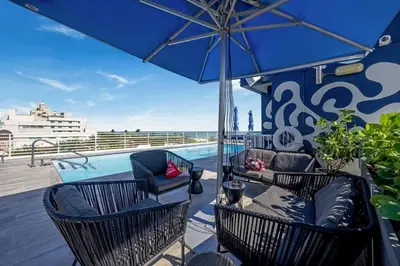 a patio with chairs and an umbrella and a pool at Cozy Studio Ocean Drive - Roof Top Pool with Bar in Miami Beach