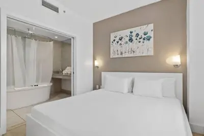 a white bedroom with a large bed and a bath tub at Miami Ocean Drive 1BR APT & Rooftop Pool Access in Miami Beach