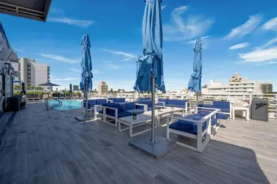 a patio with blue chairs and umbrellas on a roof at Miami Ocean Drive 1BR APT & Rooftop Pool Access in Miami Beach
