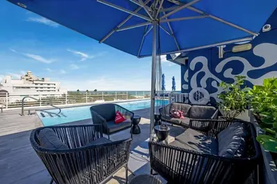 a patio with chairs and an umbrella and a pool at Ocean Dr 1BR Apt with Rooftop Pool 93 Walk Score in Miami Beach