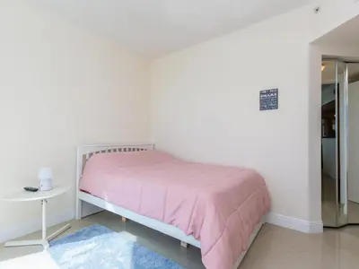 a white bedroom with a pink bed and a table at Lovely 2-Bedroom Oceanfront condo in Sunny Isles Beach