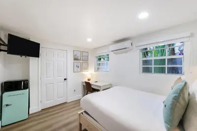 a white bedroom with a bed and a desk at The Victoria Hotel in Fort Lauderdale