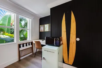 a room with a refrigerator and a surfboard on the wall at The Victoria Hotel in Fort Lauderdale