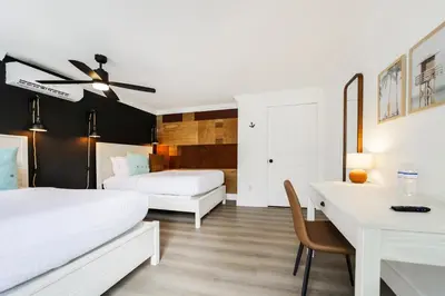 a bedroom with two beds and a desk and a table at The Victoria Hotel in Fort Lauderdale