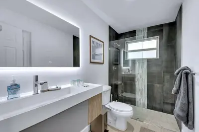 a white bathroom with a sink and a toilet at Stylish 2BR Retreat in Miamis Design District in Miami