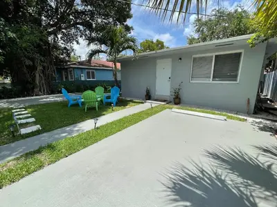 a house with a yard with blue and green chairs at Stylish 2BR Retreat in Miamis Design District in Miami