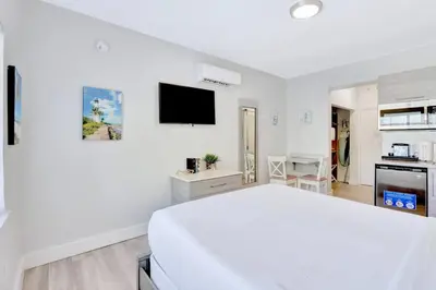 a white bedroom with a bed and a tv at Sunny Beach Studio Steps to Ocean and Nightlife in Miami Beach