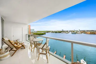 a balcony with chairs and a view of the water at Waterfront 2BR Unit with Bayview Boho Style Stunning Sunset Pool Hot Tub Gym in Sunny Isles Beach