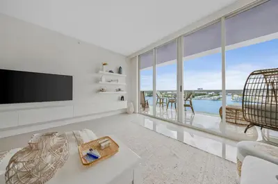 a living room with a tv and large windows at Waterfront 2BR Unit with Bayview Boho Style Stunning Sunset Pool Hot Tub Gym in Sunny Isles Beach