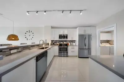 a kitchen with white cabinets and stainless steel appliances at Waterfront 2BR Unit with Bayview Boho Style Stunning Sunset Pool Hot Tub Gym in Sunny Isles Beach