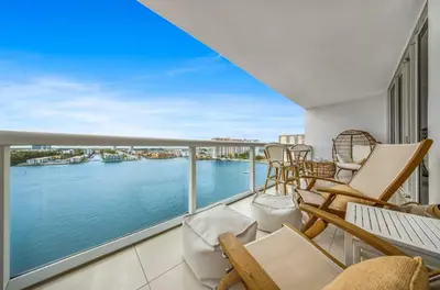 a balcony with chairs and a view of the water at Waterfront 2BR Unit with Bayview Boho Style Stunning Sunset Pool Hot Tub Gym in Sunny Isles Beach