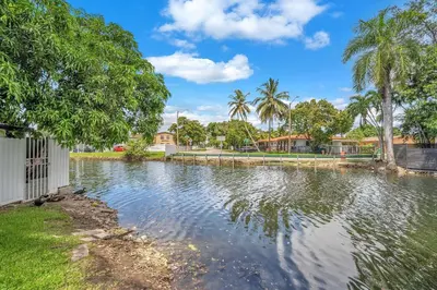 a pool of water with palm trees in a yard at Costerra Miami 2BR in Miami
