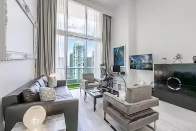 a living room with a couch and a large window at Beautiful Icon Brickell Double height ceiling in Miami