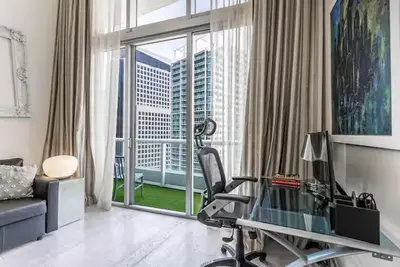 a living room with a desk and a chair in front of a window at Beautiful Icon Brickell Double height ceiling in Miami