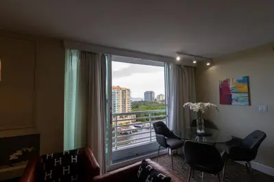a living room with a table and a large window at Luxury Waterfront Condo Hilton Hotel Amenities Beach Pool Jacuzzi Jetskis Gym in Fort Lauderdale
