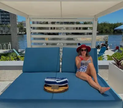 a woman in a bikini sitting on a blue bed at Luxury Waterfront Condo Hilton Hotel Amenities Beach Pool Jacuzzi Jetskis Gym in Fort Lauderdale