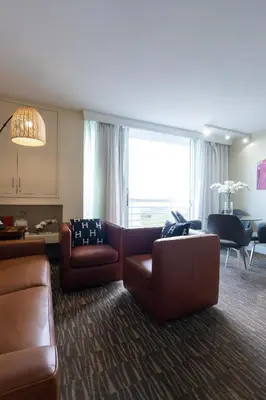 a living room with brown leather furniture and a large window at Luxury Waterfront Condo Hilton Hotel Amenities Beach Pool Jacuzzi Jetskis Gym in Fort Lauderdale